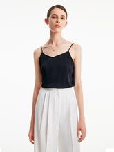 A woman wears a black camisole top.